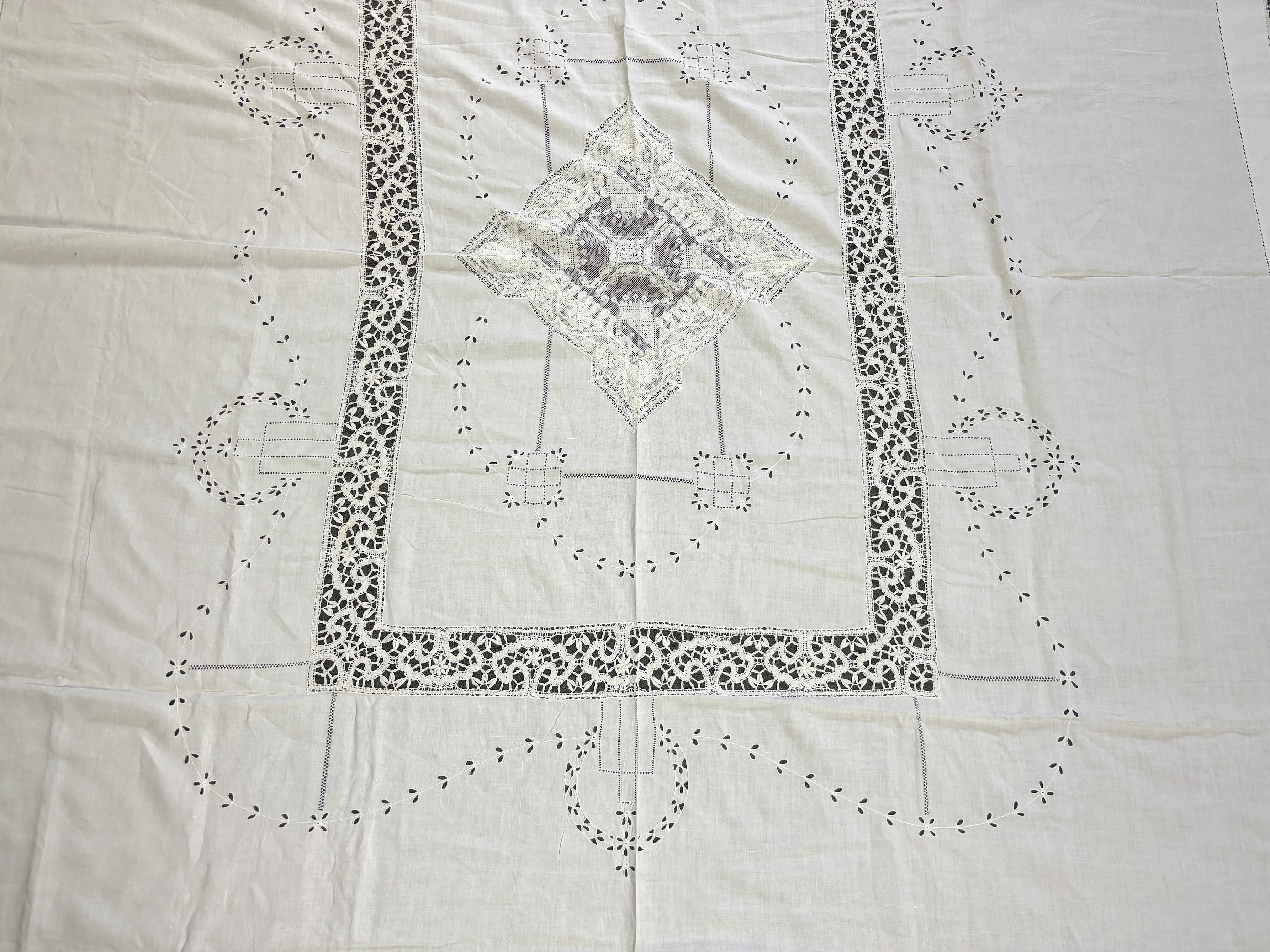An Edwardian damask banqueting cloth 354cm long x 232 wide, worked with a central needle lace inserted cartouche, together with a smaller linen table cloth, 264cm long x 226cm wide, bordered with bobbin lace edges and si